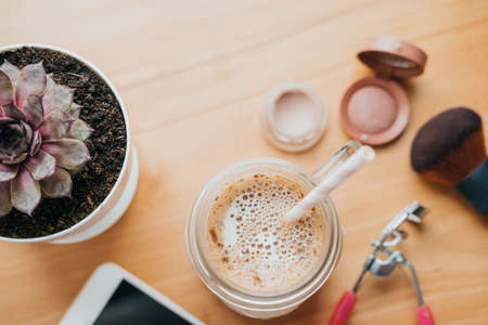 Flat lay background with Phone, rouge, shadows, house plant, coffee on the tableの写真素材