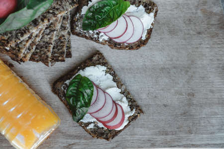 Fitness bread with cottage cheese, radish and basil and Orange juice on rustic wood background, closeupの写真素材