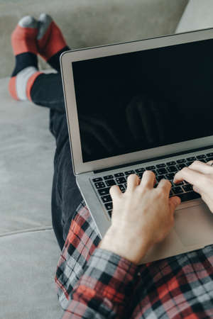 Hipster man in red socks working at laptop and lying  on the couchの写真素材