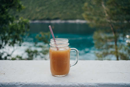 Vitamin orange juice in a glass tube on the background of the turquoise seaの写真素材