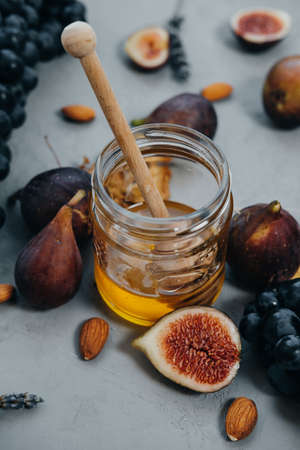 Closeup of Dark grapes, figs, honey and almonds on a gray backgroundの写真素材