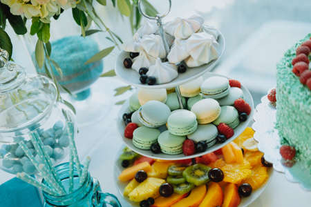 Sweet table with colorful macaroons, fruits and cake