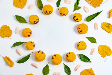 Top View Halloween with fake pumpkins and tangerines with painted scary faces candy jaw and autumn leaves on White Backgroundの写真素材