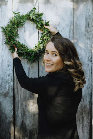 Portrait of cute woman hanging a Christmas wreath on her homeの写真素材