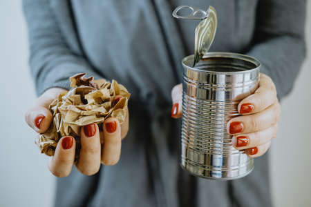 Female hands with an iron jar and paper. Separate collection of garbageの写真素材