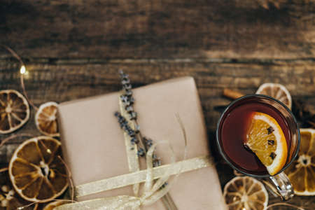Hot mulled wine with spices and gift box on wooden table. Top viewの写真素材