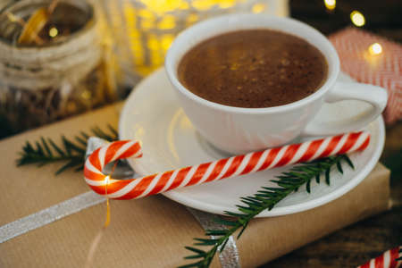 Cup of Hot chocolate with present, candy canes and Fir tree branch on dark wooden background. Selective focusの写真素材