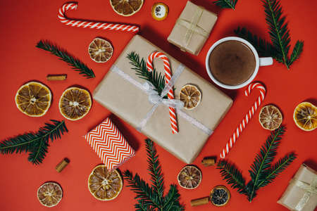 Christmas background with fir tree, hot chocolate, gift, candy canes on red board. Top view with copy spaceの写真素材