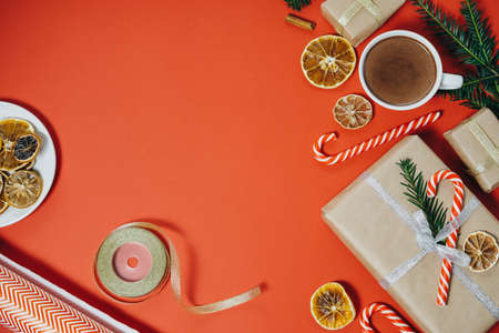 Holiday background with fir tree, hot chocolate, gift, candy canes on red board. Top view with copy spaceの写真素材