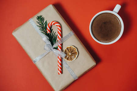 Christmas concept. Hot chocolate with fir tree, gift, candy canes on red board. Top view with copy spaceの写真素材