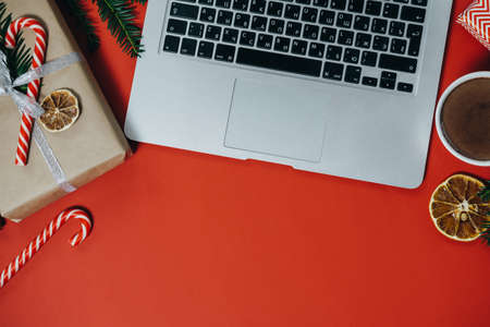 Christmas work space with laptop, hot chocolate, candies on red background. Top view, space for textの写真素材