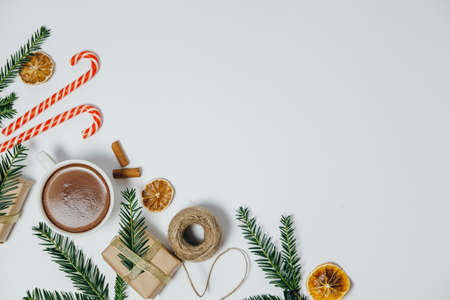 Christmas background with fir tree, hot chocolate, gift, candy canes on white board. Top view with copy spaceの写真素材