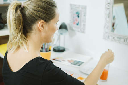 Back view of artist with paintbrush at the workplace の写真素材