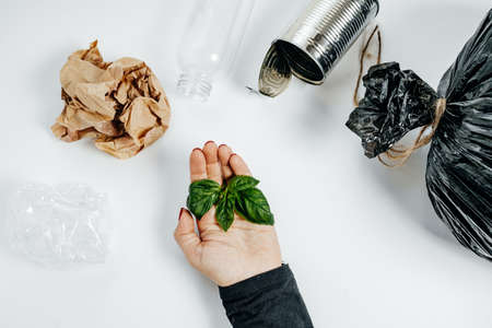 Waste management concept. Woman Hands With Green leaf and garbage on the White Background. Top Viewの写真素材