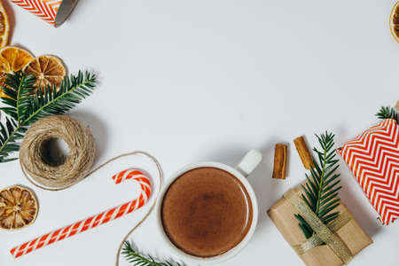 Christmas background with fir tree, hot chocolate, gift, candy canes on white board. Top view with copy spaceの写真素材