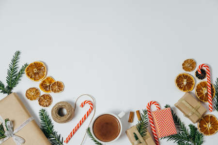 Christmas decoration with fir tree, hot chocolate, gift, candy canes on white board. Top view with copy spaceの写真素材