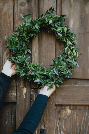 Closeup Christmas wreath in woman hands against her homeの写真素材