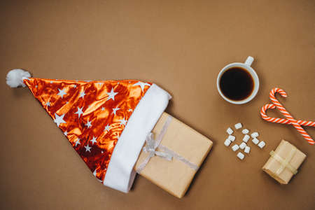 Christmas background with santa hat, Coffee with marshmallows and gifts on brown table. Top view, flat layの写真素材