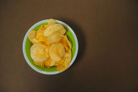 Chips in a bowl on a brown table. Top viewの写真素材