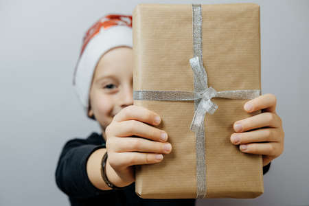 Cute boy in red santa hat with gift. Christmas conceptの写真素材