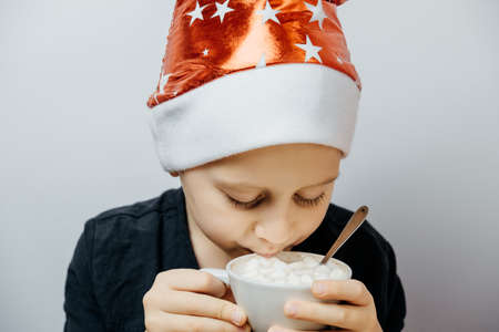 Cute boy in a red hat and drink cocoa in a mug. Christmas conceptの写真素材