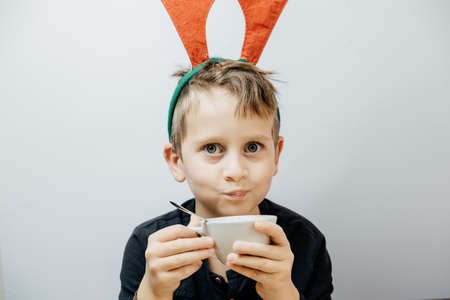 Cute boy in a red deer horns drink cocoa in a mug. Christmas conceptの写真素材