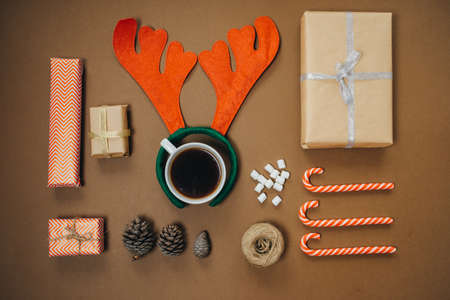 Christmas background with santa hat, Coffee with marshmallows and gifts on brown table. Top view,...