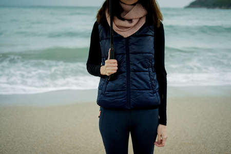 Closeup  woman standing with an umbrella in front sea in winter or autumnの写真素材