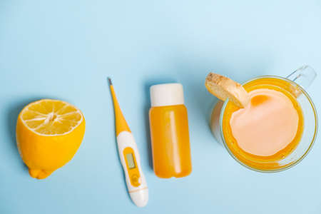 Ginger shot healthy drink with curd in a plastic bottle and thermometer on blue background. Immunity Boosting Tonic. Space for textの写真素材