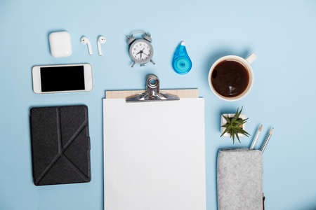 Stationery, phone, coffee and headphones on blue office table. Top view, Flat lay. の写真素材