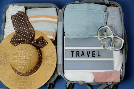 Travel board in Open suitcase packed with clothes. Summer vacations. Top view