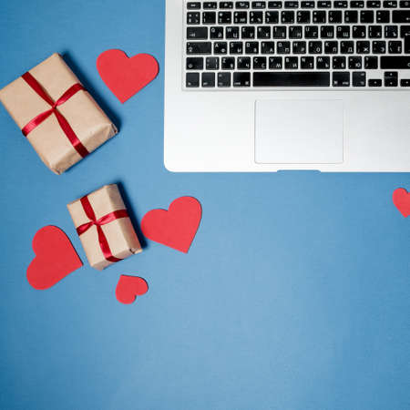 Flat lay woman office desk. Workspace with laptop, pink carnation, stationery on blue table. Top viewの写真素材