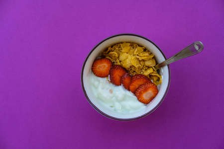 Useful breakfast: yoghurt with strawberries and fruits on a purple backgroundの写真素材