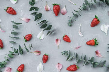 Flat lay summer composition with strawberries, petals of flowers on a gray background. Top viewの写真素材
