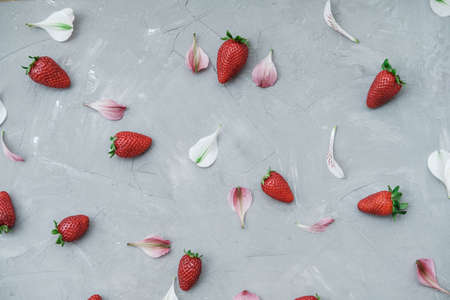 Flat lay summer composition with strawberries, petals of flowers on a gray background. Top viewの写真素材