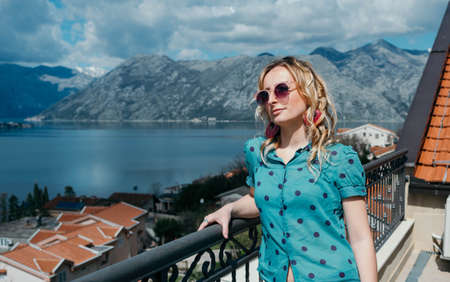 Pretty blonde hair woman enjoys the view of the sea and mountains in the Boka-Kotorsky bay,...