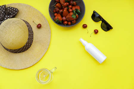 Summer background on the yellow table: Straw Hat, soda, berries sunscreen and glasses. Top view, flat layの写真素材