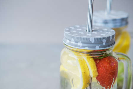 Fruit water with lemon and strawberries in a glass jarの写真素材