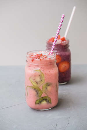 Berry smoothies with strawberries and blueberries in a glass jar on a gray background
