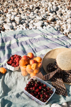 Summer composition with hat, berries and sunglasses on a pebbles beach near seaの写真素材