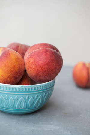 Ripe Organic Peach in blue ceramic bowl in grey backgroundの写真素材