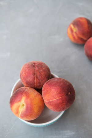 Ripe Organic Peach in blue ceramic bowl in grey backgroundの写真素材