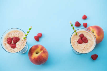 Peach smoothies with milk (yogurt), raspberries and striped straws. Blue background. Copy space top viewの写真素材