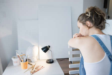 In search of inspiration. Sad Woman painter in front of the canvas and drawing. Artist studio...