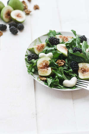 Salad with arugula figs blackberry and walnut on white table. Top viewの写真素材