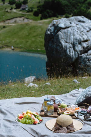 Fruit, lemonade and pastries served at a picnic against mountains with lake in Montenegroの写真素材