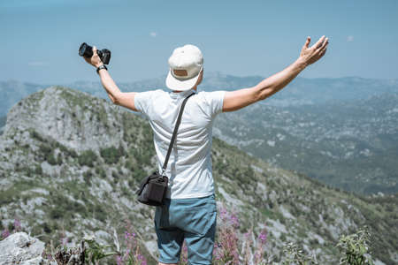 Traveler man in a cap and sunglasses raised his hands up and see beautiful scenery   mountain landscape in Montenegroの写真素材