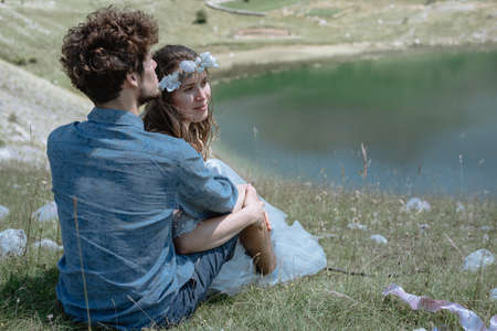 Stylish Romantic couple sit by the lake against the background of the mountains.の写真素材