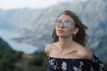 Portrait of Young stylish curly blonde woman in shorts and crochet tops and sunglasses against the...