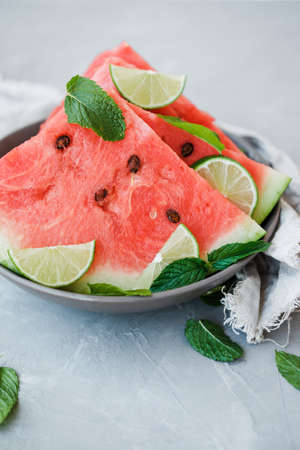 Watermelon slices and lime on a plate on a gray background